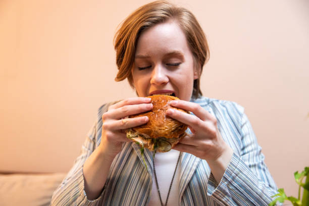 istock Young woman enjoying eating burger and drinking cocktail 1393130730
