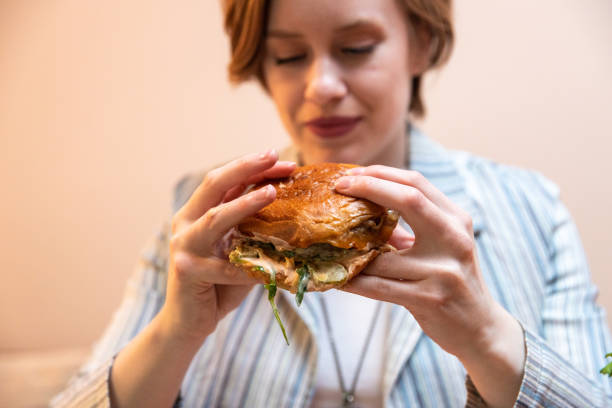 istock Young woman enjoying eating burger and drinking cocktail 1393131477