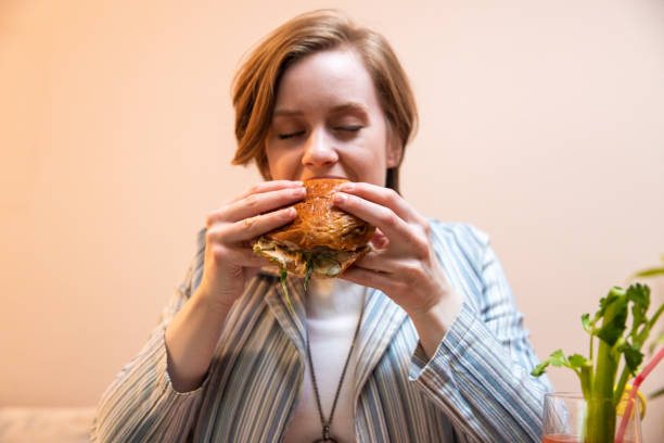 istock Young woman enjoying eating burger and drinking cocktail 1393131545