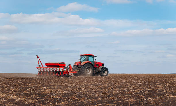 istock Spring sowing season. Farmer with a tractor sows corn seeds on his field. Planting corn with trailed planter. Farming seeding. The concept of agriculture and agricultural machinery. 1393131939