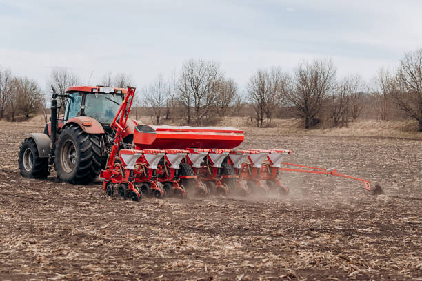 istock Spring sowing season. Farmer with a tractor sows corn seeds on his field. Planting corn with trailed planter. Farming seeding. The concept of agriculture and agricultural machinery. 1393132257