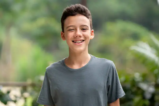 Photo of Teen boy with braces smiling outside in summer