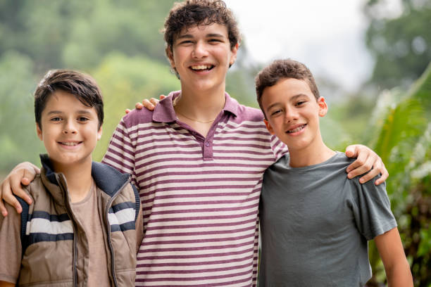 amigos adolescentes sonrientes parados afuera juntos en verano - three boys fotografías e imágenes de stock