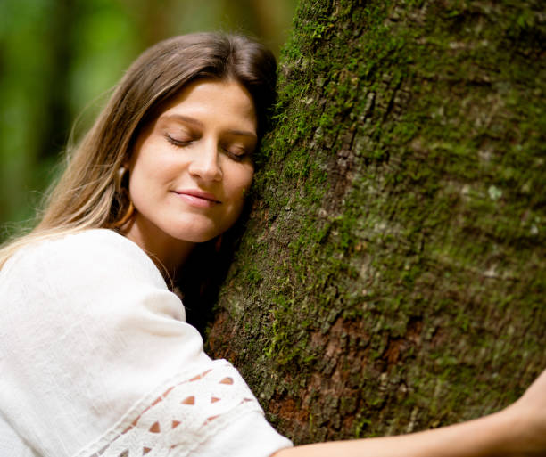 istock Young woman hugging a tree trunk with her eyes closed 1393138213