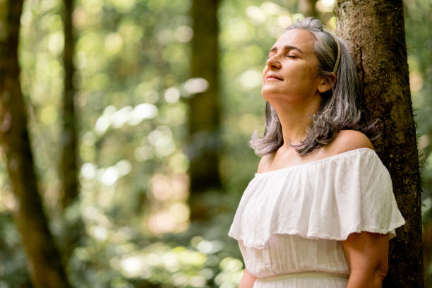 istock Mature woman leaning on a tree with her eyes closed 1393138226