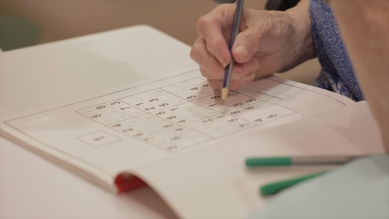 Elderly woman completes a sudoku puzzle to help prevent dementia