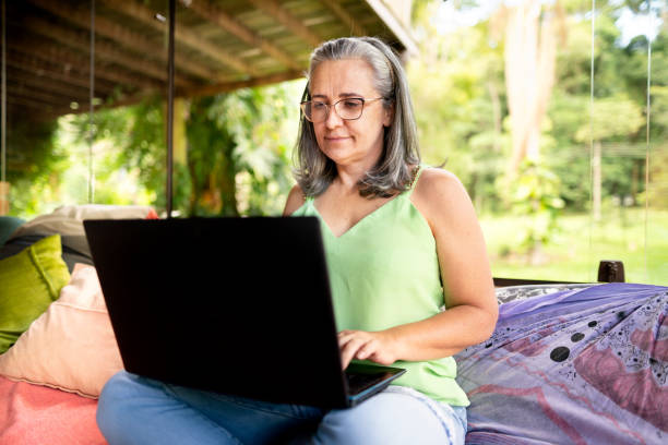 istock Mature woman using a laptop on a sofa in her sunroom 1393139398