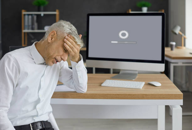 istock Office worker sitting in front of desktop computer and waiting for system to load 1393140939