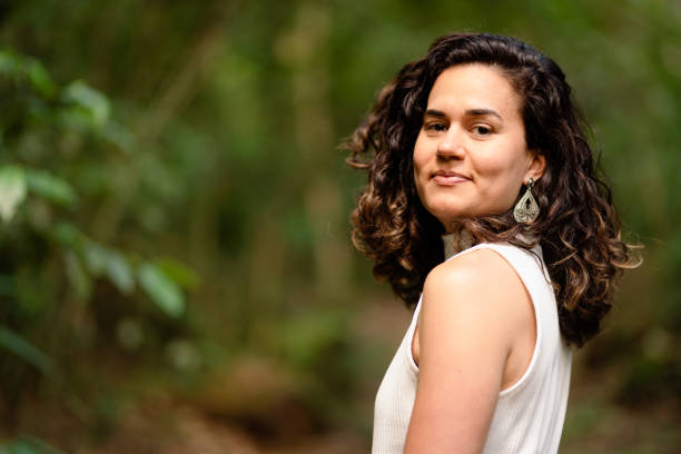 istock Young woman smiling while standing alone in a forest clearing 