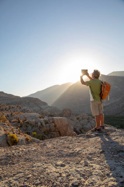 hiker takes photo with digital tablet at sunrise - travel ipad isolated backpack imagens e fotografias de stock