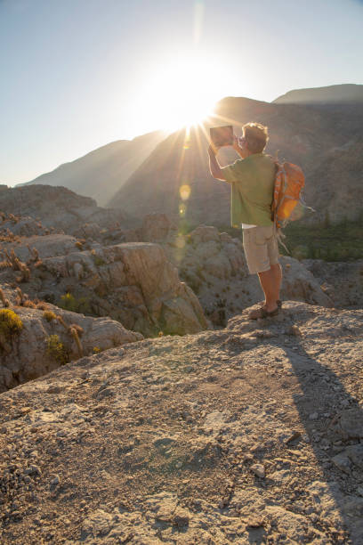 istock Hiker takes photo with digital tablet at sunrise 1393142332