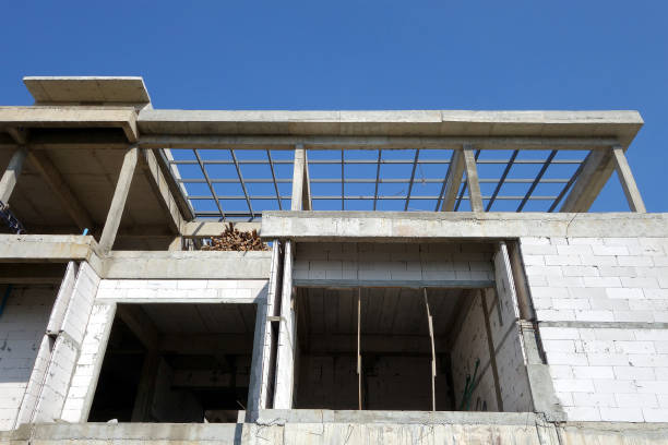 mur de blocs de briques nues et structure de piliers en béton des maisons en construction avec fond de ciel bleu clair - block blue brick building activity photos et images de collection