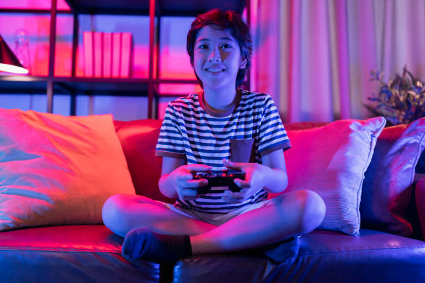 istock Exited smiling cheerful asian Teenager boy playing mobile game smartphone application on sofa in living room at home,Asian child male Sitting on a couch using smartphone having fun playing a game on mobile at night 1393146877