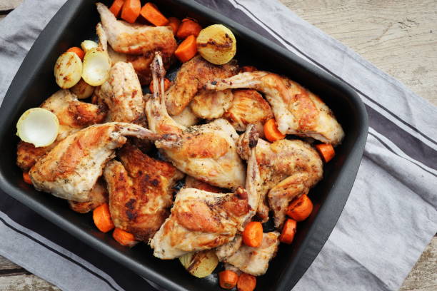istock Roasted Rabbit Haunches in Pan with Stewed Vegetables on Rustic Wooden Table Surface 1393150035