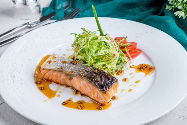 istock Salmon steak on the grill with sauce and vegetables 1393150724