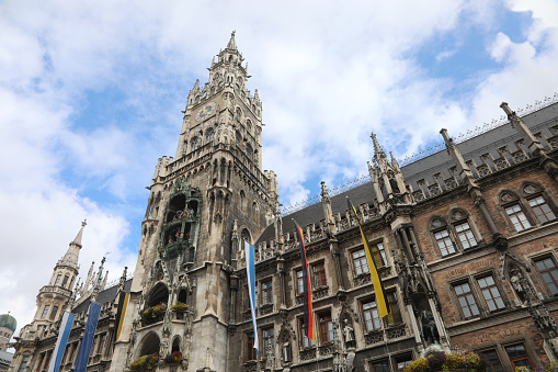High clock tower of the new town hall of Munich in Germany and the flags of the city and the region