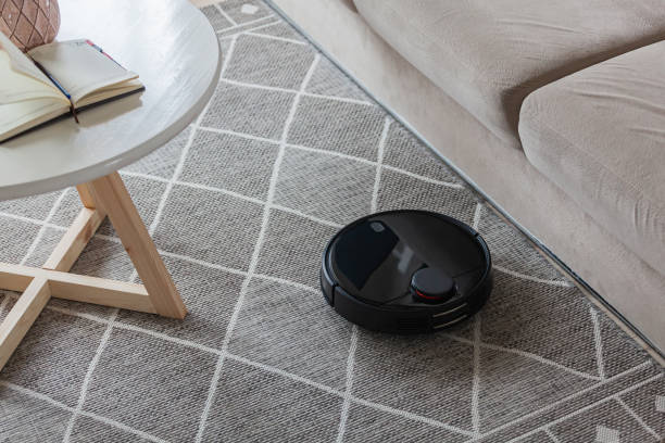 istock Robotic vacuum cleaner cleaning carpet at home next sofa 1393153345