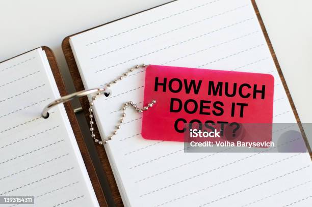 How Much Does It Cost Business Concept Red Card Text On The Background Of An Open Notepad On The Table Stock Photo - Download Image Now