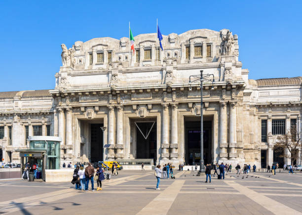 Main hall of Roma Termini railway station building on October 21st, 2024. Travellers and people walk by or wait near large arrivals and departures boards, surrounded by shops and bright advertisements. Roma Termini station is Rome’s largest train transportation hub.