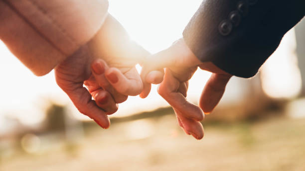 istock Closeup image of two lovers holding hands at sunset - Trust, love, relationship and support concept 1393157432