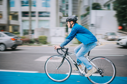 Asian chinese man cycling in the city on bicycle lane to work sustainability lifestyle