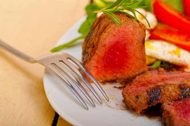 beef filet mignon grilled with fresh vegetables on side ,mushrooms tomato and arugula salad