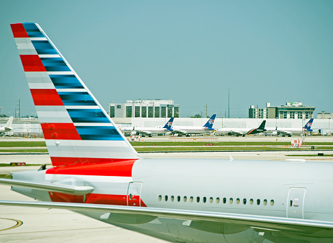 Boeing 777 tail plane in American Airlines livery with row of aircraft in background, Miami Airport, Florida, U.S.A. Miami International Airport, MIA, previously Wilcox Field, is the main airport in Florida serving the United States and international destinations, including Latin America.