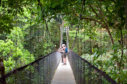 Tourists on Mistico hanging bridge, Volcan Arenal National Park, Arenal, Costa Rica. The Hanging Bridges are a feature of Arenal National Park, where visitors enjoy views high in the tropical rainforest canopy. . Costa Rica is the central American country north of Panama that is renowned for its tropical birdlife, exotic wildlife and adventure pursuits such as whitewater rafting, parasailing and ziplining