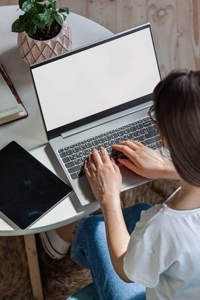 istock Young woman using laptop screen blank, mock up, work home, top view 1393166120