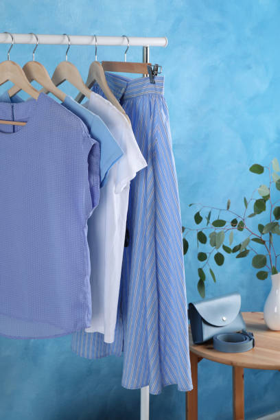 istock Rack with stylish clothes near light blue wall indoors 1393167464