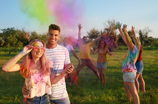 Happy friends with colorful powder dyes outdoors. Holi festival celebration