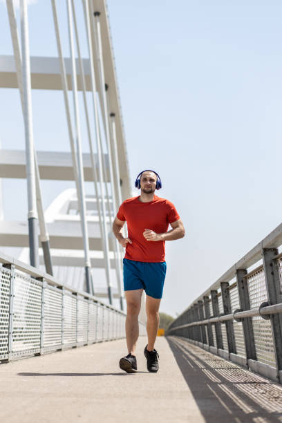istock Hand amputee athlete running on a bridge with headphones 1393170620