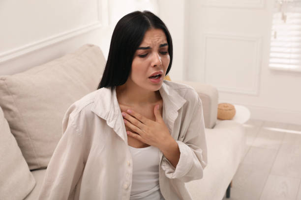 jeune femme souffrant de problèmes respiratoires sur un canapé à la maison - sifflement photos et images de collection