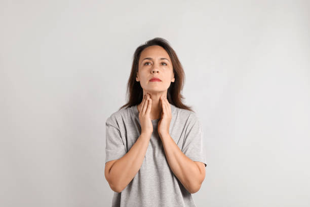 Mature woman doing thyroid self examination on light background Mature woman doing thyroid self examination on light background thyroid gland stock pictures, royalty-free photos & images