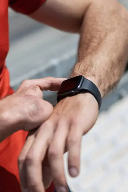 Closeup of a hand amputee athlete checking his workout progress on a smart watch - iWatch. Athlete with a hand disability. Hand amputee athlete motivated and healthy.