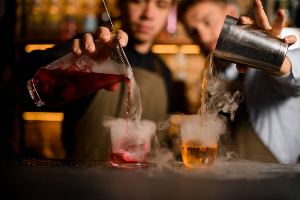 istock front view of two transparent glasses with ice, into which bartenders carefully pour various steaming cocktails 1393172910