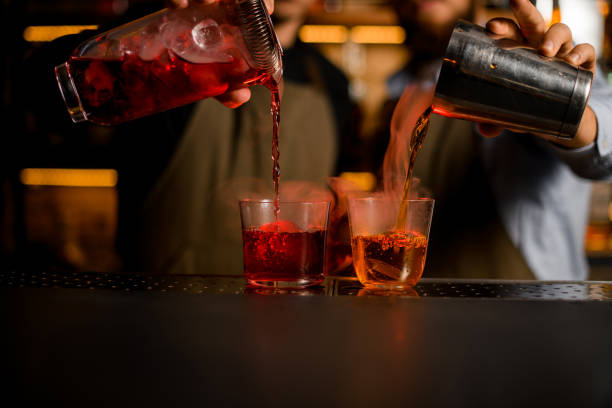 istock two transparent glasses with ice, into which bartenders carefully pour various bright steaming cocktails 1393172919
