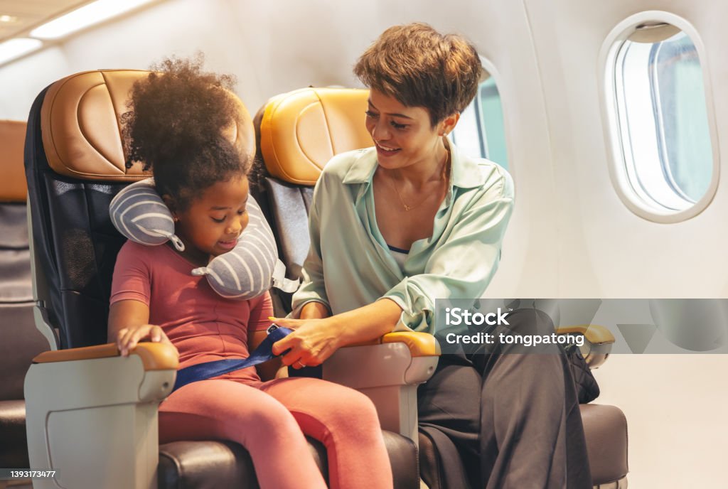 The child's safety belt is being fastened by mom. Airplane Stock Photo
