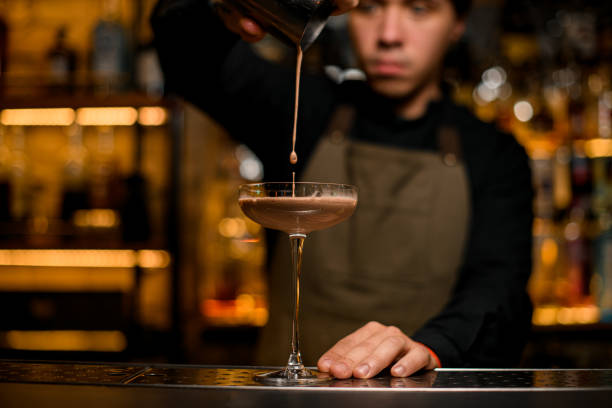istock beautiful cocktail glass into which drink is being poured from shaker 1393173505
