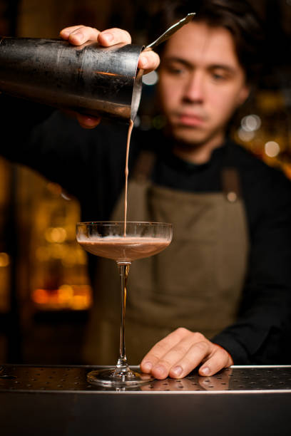 istock selective focus on glass into which cocktail is being poured from shaker 1393173636