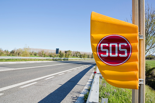 SOS sign on yellow plastic phone box on highway