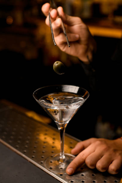 istock Barman using tweezers to put an olive into martini glass 1393176318