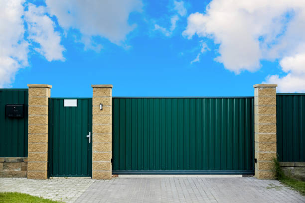 istock Green metal profile fence with block posts. Entry group: gate, wicket and postbox. Opaque surface, vertical lines. Security. Private property fencing. Exterior. Pavement tiles on parking. Isolated 1393176500