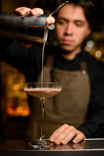 istock bartender professionally pours brown cocktail from shaker into glass 1393177295