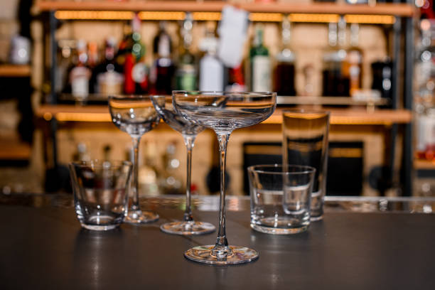 istock Set of empty crystal clean glasses on dark bar counter. 1393178724