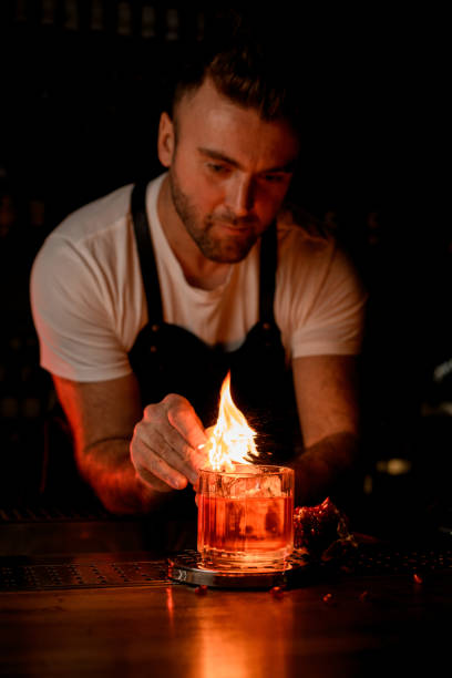 istock male bartender carefully lights a fire over a glass with a drink and ice 1393179839