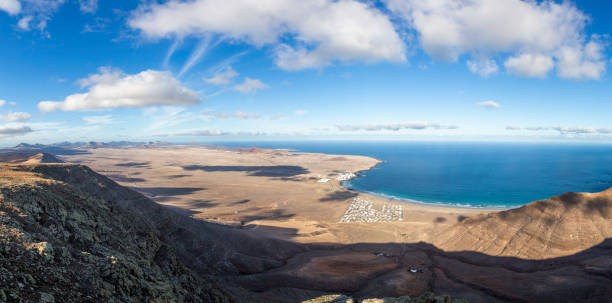 Panorama of El Jable desert and Famara village, Spain Panorama of El Jable desert and Famara village, Lanzarote, Spain caleta de famara lanzarote stock pictures, royalty-free photos & images