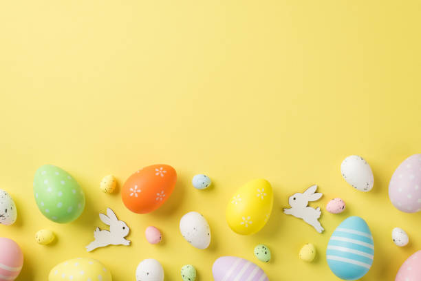 istock Top view of multicolored Easter eggs and quail ones with two white rabbits situated on the isolated yellow background copyspace 1393182347