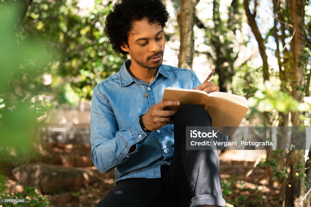 man writing in notebook ideas and enjoying nature serious man writing in notebook ideas and enjoying nature in wooded area Diary Stock Photo