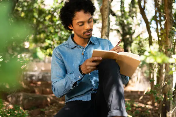 Photo of man writing in notebook ideas and enjoying nature